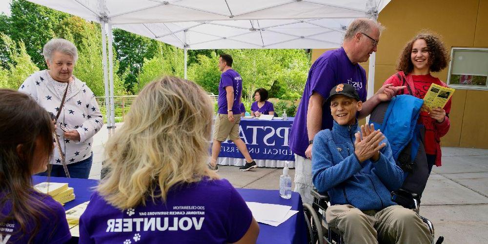 在罗莎蒙德·吉福德动物园举行的全国癌症幸存者日庆祝活动上，志愿者们正在登记表旁帮助一名癌症患者.